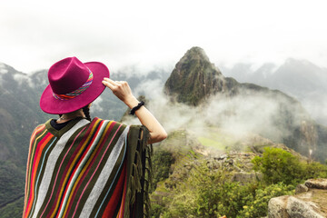 A female tourist in a hat and a Peruvian poncho against the background of Machu Picchu. Cusco. Peru