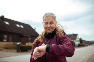 Senior woman checking smartwatch during outdoor exercise