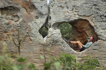 mulher sentada em pedra furada no vale do catimbau, pernambuco, trilha das umburanas