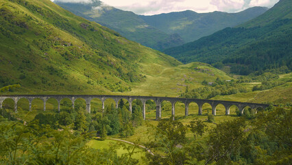 Wonderful play of sun and shadows on green slope behind famous railway viaduct