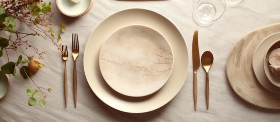 A top-down view of a dining table beautifully set with ceramic plates, silverware, and fresh flowers as decoration. The table is made of wood and marble, illuminated softly by natural light.