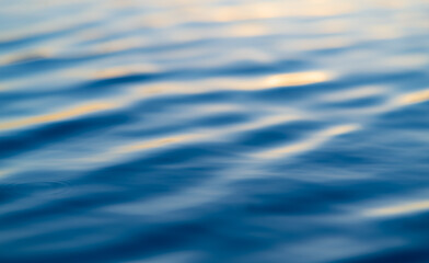 Blurred liquid background with bright blue and orange colors. Wavy water surface with reflection of blue evening sky at sunset. Blue hour twilight at a big lake in Sauerland, Germany. 