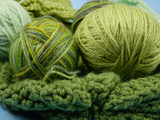 Knitted item from   green yarn and a set of the different balls of wool in the green tones for hand knitting,  background
