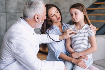 Pediatrician checking up patient girl using stethoscope during home visit