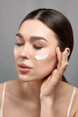 Closeup happy young woman applying cream to her face Skin care and cosmetics concept. Cosmetics. Beauty Woman face skin care.Natural makeup, touching face.