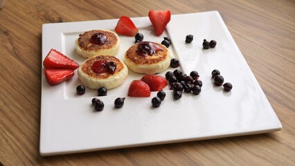 Savor aroma of fresh cottage cheese pancakes adorned with juicy berries Watch as hand eagerly grabs one of pancakes indulging in its deliciousness Cottage cheese pancakes are treat for any occasion
