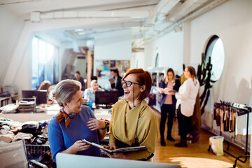 Two female designers laughing in a lively office workspace