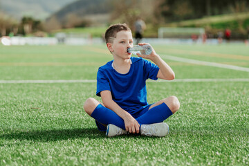 Boy soccer player hydrating during break