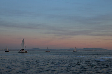 Fototapeta premium Sailboats on a vast sea during sunset