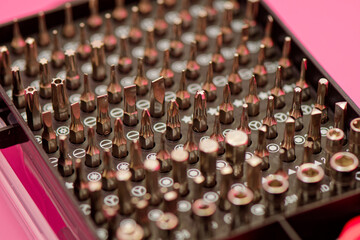 Screwdriver bit set close up photo on a pink background. Bits for screwdriver in box. Repairing smartphone concept. Advertising purposes