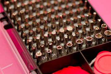 Screwdriver bit set close up photo on a pink background. Bits for screwdriver in box. Repairing...
