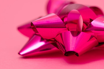 Glossy wrapping bow on a pink background. Bright pink wrapping bow, gift ribbon. Close-up. Studio...