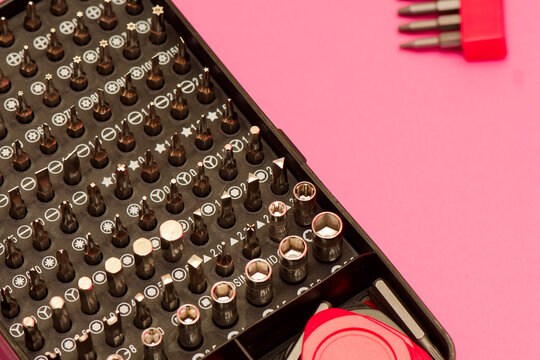 Screwdriver bit set close up photo on a pink background. Bits for screwdriver in box. Repairing smartphone concept. Advertising purposes