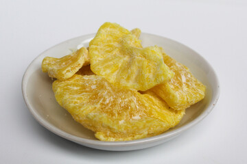 Dried pineapple sweets. Candied and dried pineapple. On small white plate. Isolated on white background