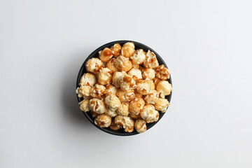 Caramel popcorn, in a black bowl, isolated on white background, flat lay or top view