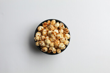 Caramel popcorn, in a black bowl, isolated on white background, flat lay or top view