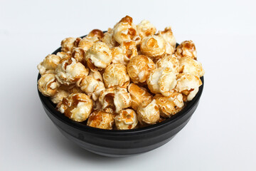 Caramel popcorn, in a black bowl, isolated on white background