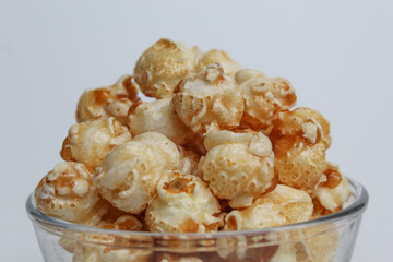 Caramel popcorn, in a transparent glass bowl, isolated on white background