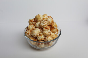 Caramel popcorn, in a transparent glass bowl, isolated on white background
