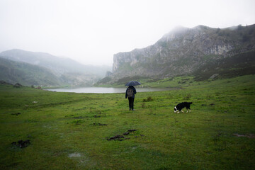 Unrecognizable man with umbrella and raincoat walking in the lakes of Covadonga. Asturias - Spain