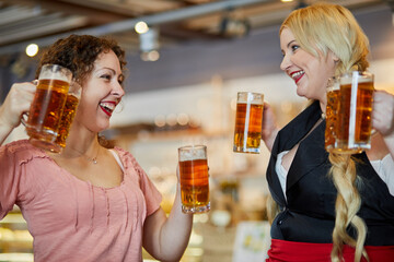 Two laughing women with glass mugs with beer