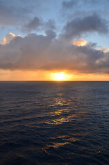 Orange sunset at set, reflections of sun rays on rippled water surface, cloudy sky, concept for traveling and tourism 