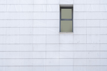Small gray aluminum rectangular window on a white tiled wall
