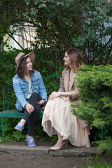 Pretty friends talking and sitting on a park bench outdoors