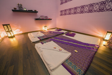 Empty pink cozy room with mats for thai massage and lamps on floor