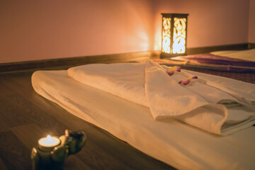 Empty cozy room with mat with white towel for thai massage and lamp on floor