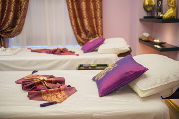 Two lounges for thai massage with towels, pillows and flowers in empty room