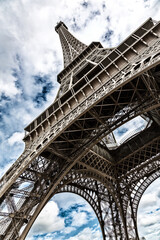 Eiffel Tower with blue sky and cloud background. Low angle view looking up. Built by engineer Gustave Eiffel, and opened in 1889. Champ de Mars, Paris, France. - 755693076