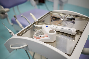 Model of human jaw with teeth, electrical toothbrush and glasses at dentist office, shallow dof