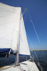 Big sail of modern white yacht sailing on river at summer sunny day