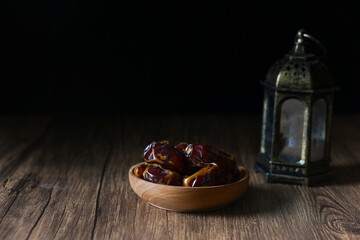 Dried dates served on wooden bowls and lanterns with Arabic calligraphy meaning 