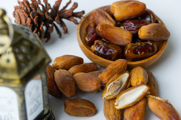 a close-up photo of dried dates served on a wooden bowl and lantern with Arabic calligraphy meaning 