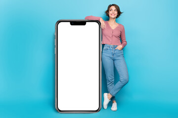 Photo pretty lady posing near big smartphone screen display new phone model advert promo isolated blue color background - obrazy, fototapety, plakaty