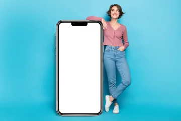 Foto auf Acrylglas Photo pretty lady posing near big smartphone screen display new phone model advert promo isolated blue color background © deagreez