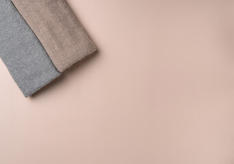 Two towels on pastel pink background.