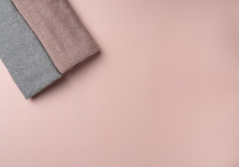 Two towels on pastel pink background.