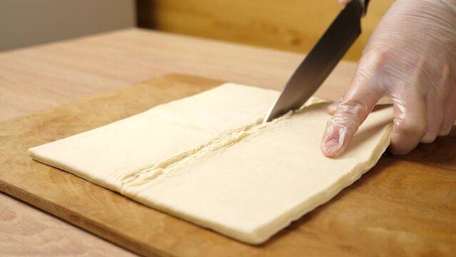 Cut the puff pastry in half with a knife. Making puff pastry pies.