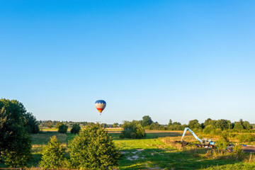 Hot air balloon flying over the field in the evening. Beautiful summer landscape.