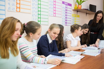 Young teacher is giving a task to her seven students in classroom