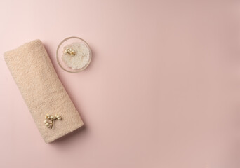 Towel with sea salt on pastel pink background. Spa concept