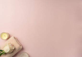Towel with sea salt, soap and rose on pastel pink background. Spa concept