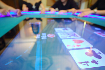 Electronic table in modern casino and hands of four players out of focus