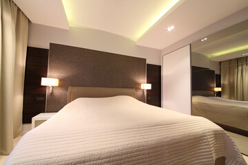 Large bed and wardrobe with mirror in bedroom interior of modern flat