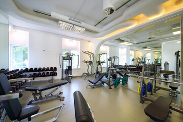 Fototapeta na wymiar Empty modern gym with new shiny fitness equipment, dumbbell set for sport training