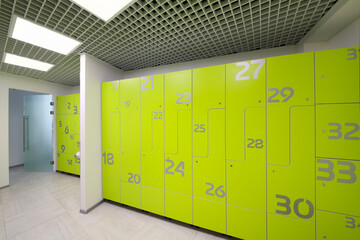 Empty bright modern cloakroom in gym with many green lockers