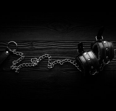Black hand cuffs over dark wooden background